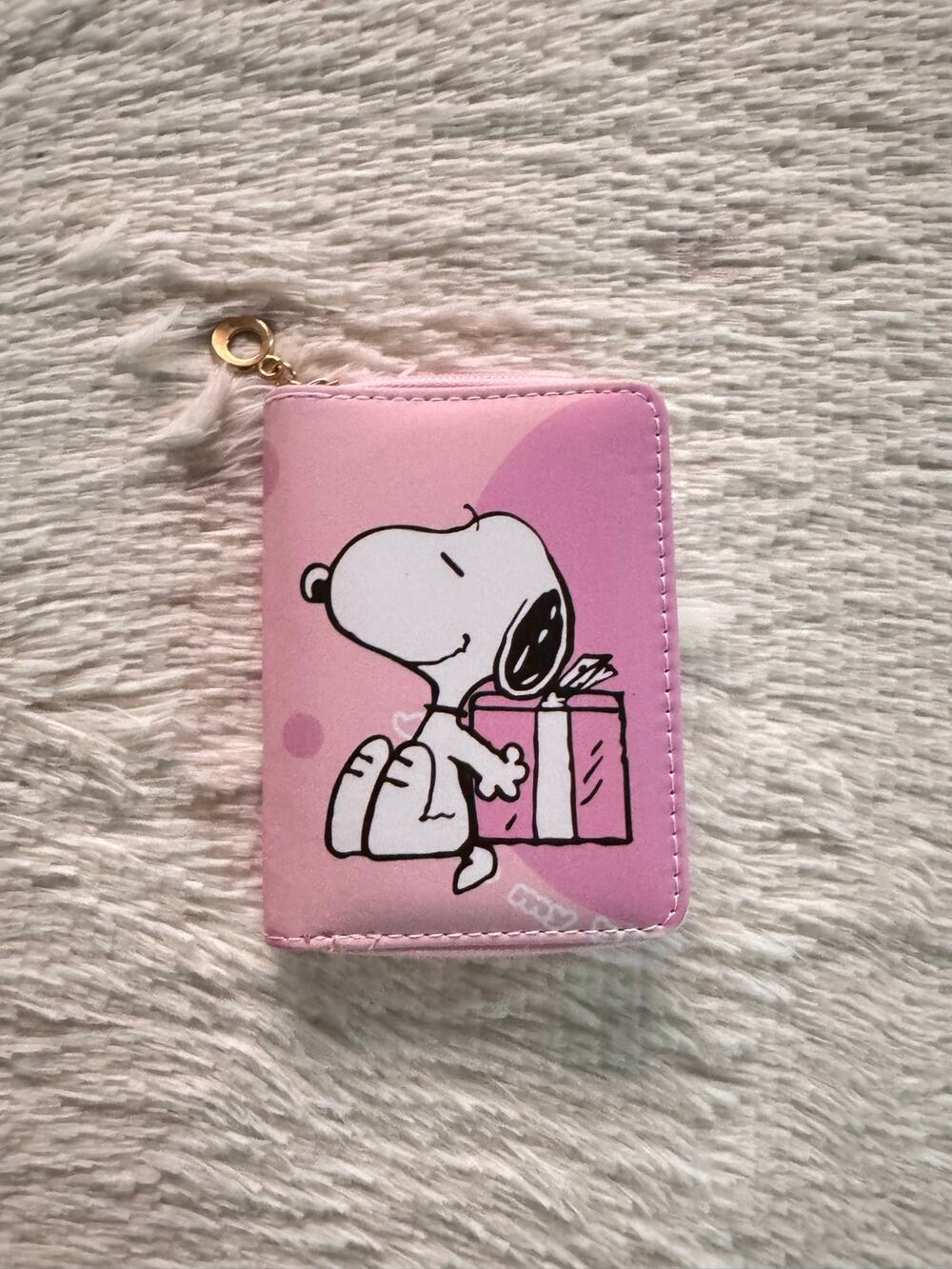 Pink Snoopy wallet zipper holding a gift box